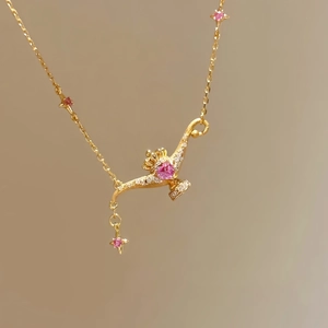 Close-up of gold magic lamp necklace with a pink heart gemstone and sparkling crystal details