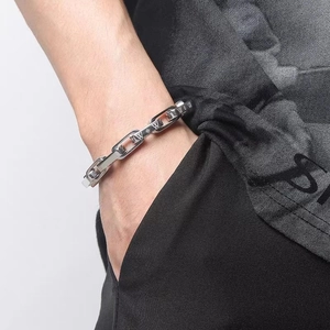Detail of silver titanium steel chain bracelet with W letter links on male model wrist