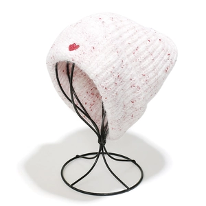 Close-up of white knit beanie with red speckled wool texture and a red heart logo