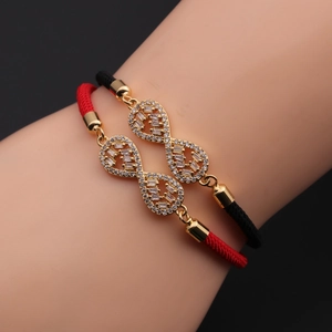 Close-up of infinity symbol bracelets with gold finish and rhinestones on woven cords