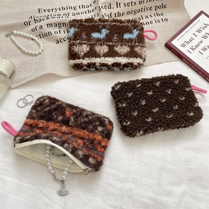 Detail of plush zippered pouches in heart and stripe patterns with pearl jewelry