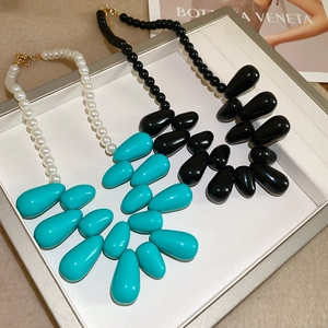 Détail de colliers avec pendentifs goutte d'eau en acrylique bleu-blanc et noir poli
