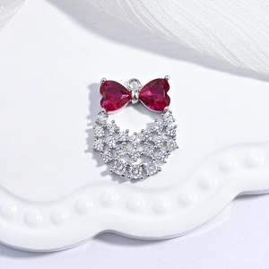 Detail of waterdrop pendant with red bow gemstone and white round gems on silver base