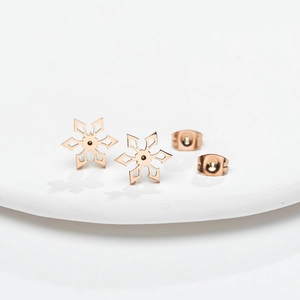 Elegant rose gold snowflake stud earrings with intricate cutout design on white stand