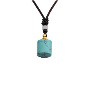 Detail of turquoise cylinder pendant with golden cap and brown braided necklace cord