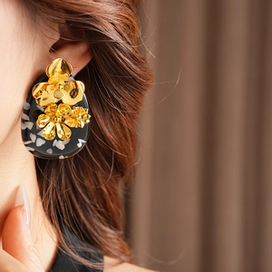 Detail shot of a vintage gold floral earring with black speckled resin base