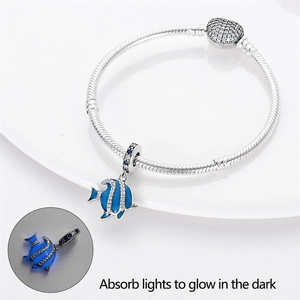Close-up of luminous blue fish charm on silver bracelet showing glow in the dark feature