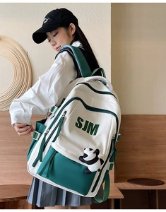 Detail of white and green canvas backpack featuring SJM letter print and panda keychain