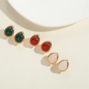 Detailed shot of teardrop earrings with green, red, and pink stones in gold frames