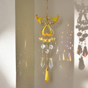 Hanging angel heart suncatcher with faceted crystals reflecting colorful light on the wall