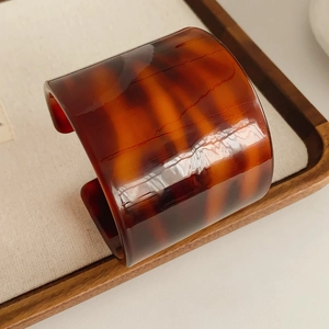 Detailed view of leopard acetate open cuff bracelet on a minimalist display tray