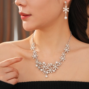 Close-up of diamond flower necklace and pearl earrings on a model in natural light