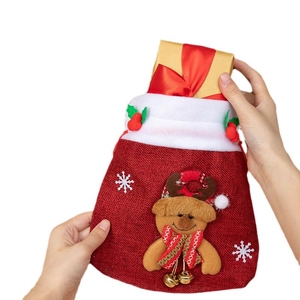 Red linen Christmas gift bag with 3D reindeer design and bell being held by hands