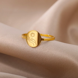 Detail of 18K gold stainless steel ring with engraved sun and palm patterns on metal surface