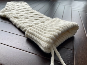 Macro detail of white cable knit Christmas stocking with ribbed cuff and textured patterns