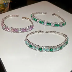 Sparkling zircon geometric heart bracelets in pink and green colors on white surface