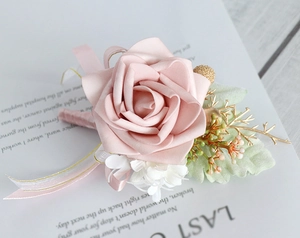 Close-up of a handmade dusty pink rose boutonniere with silk ribbons on a white card
