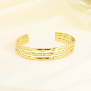 Detailed macro view of triple-layered gold stainless steel cuff with geometric V-texture