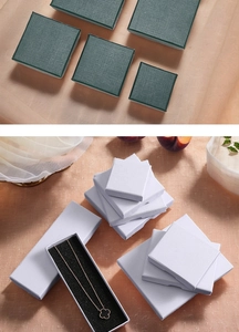 Detail view of square gift boxes in green and white with linen texture and jewelry display