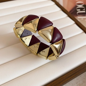 Detail of geometric wide bangle with polished gold and burgundy triangular inlay
