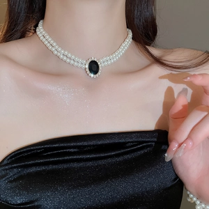 Detail of double-layer pearl choker featuring a black oval gemstone with diamond accents