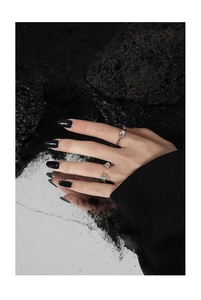Detail of artistic S925 sterling silver knotted ring on reflective mirror and lava stone