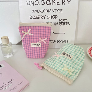 Detail of plaid makeup bags with ribbon bows and premium woven labels in soft light