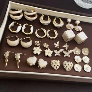 French luxury gold flower earrings set with cream enamel and pearls in leather tray