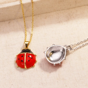 Macro view of gold and silver ladybug pendants with red enamel and hollow metal back