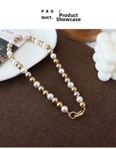 Detail of multi-color pearl necklace with gold clasp on cozy knit background