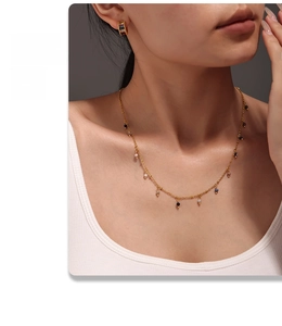 Close-up of thin 18K gold-plated layered necklace and earrings with small natural stone beads