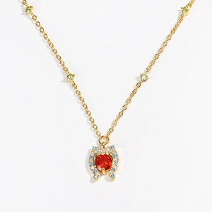 Macro shot of gold necklace with orange-red heart stone and colorful crystal accents