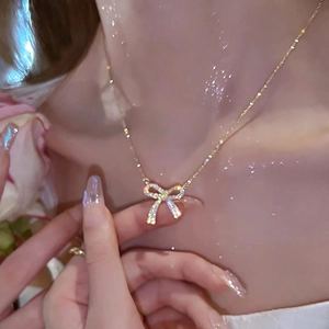Close-up of elegant gold bow pendant necklace with sparkling cubic zirconia on neck
