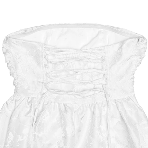 Detail of white tube dress featuring corset-style back lacing and floral lace texture
