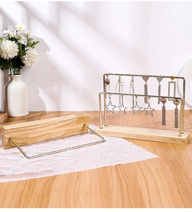 Macro detail of a double-layer gold iron earring stand with a natural beech wood base