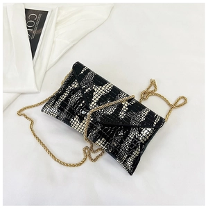 Detail shot of black and white crocodile pattern envelope bag with gold chain strap