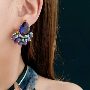 Detail of teardrop blue zircon earrings with matte purple and cyan beaded clusters