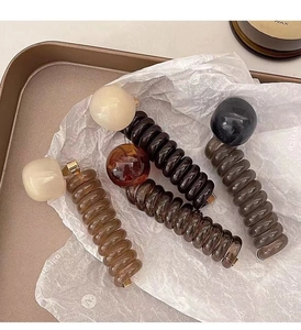 Close-up of spiral ponytail hair ties with large beads in assorted colors on a tray