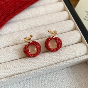 Close-up of cute red apple-shaped earrings with gold stems in jewelry box