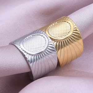 Detail of silver and gold stainless steel rings with oval grid texture on silk