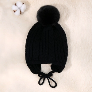 Detailed view of black cable knit baby winter hat with large pom-pom and earflaps
