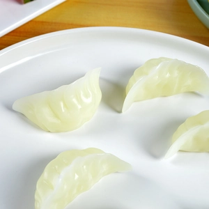 Realistic miniature dumpling food models on white plate for creative kitchen decor