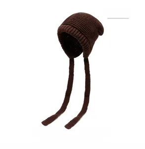 Close-up of coffee brown chunky knit earflap hat with decorative side ties