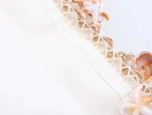 Detail view of beach dress hem featuring nautical rope trim with shell and starfish charms