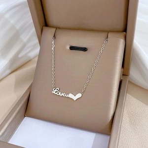 Close-up of a silver Love heart pendant necklace inside a beige luxury jewelry box