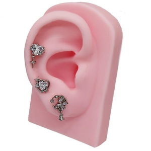 Silver heart and moon zircon cartilage earrings set shown on a pink silicone ear model
