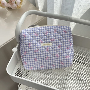 Detailed texture of quilted purple checkered makeup bag with pink bow patterns