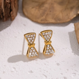 Détail macro de boucles d'oreilles nœud dorées avec cristaux brillants sur fond blanc