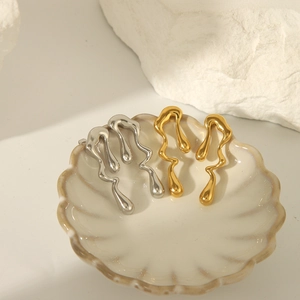 Boucles d'oreilles abstraites style lave liquide en or et argent sur plateau