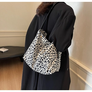 Detail of a large leopard print tote bag styled with a black coat in a chic indoor setting